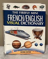 Front cover of The Firefly Mini French/English Visual Dictionary, showing colorful images including a train, planets, a fish, and a drum, indicating diverse visual content inside.