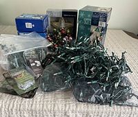 Overall view of multiple boxes of Christmas lights, green extension cord, and plastic packaging