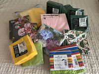 Single photo showing all packages of napkins in various sizes, colors, and patterns arranged together on a surface