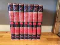 Seven hardcover volumes of the Popular Mechanics Do-It-Yourself Encyclopedia showing red and black spines with volume numbers 1,4,5,6,7,9,11