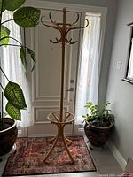 Full view of the vintage bentwood coat tree standing on a rug near a door, showing its overall height and structure.