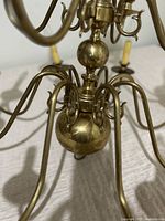 Close-up of the bottom portion of the brass chandelier showing curved arms & central decorative balls.