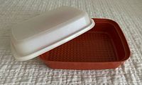 Vintage Tupperware marinating container with white lid, square red plastic base, showing textured bottom inside container.