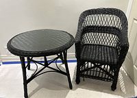 Vintage black wicker table and chair set displayed together against a plain wall, showing size and style relation.