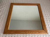 Full front view of the vintage wood framed mirror showing square shape and light natural wood frame with clear mirror.