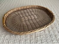 Side angled view of wicker serving tray showing the plastic insert and the natural color of woven wicker.
