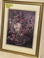 Front view of large floral and fruit print in ornate gold frame.