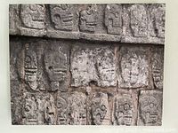 Photo showing full front of stretched canvas art print portraying multiple stone carved skulls.