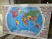 Full view of framed world map with countries and ocean details, showing the protective finish and black frame.