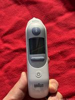 Front view of Braun ear thermometer with visible display screen and power button.