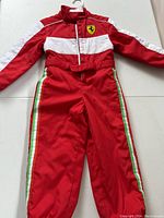 Full view of red Ferrari racing suit costume with logo and stripes, laid flat on a surface.