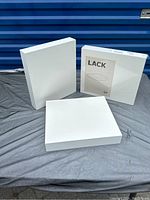Photo showing three unopened white boxes containing the floating shelves, one box is labeled IKEA LACK series.