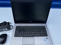 Open HP laptop showing keyboard with loose F4 key and power adapter on side.