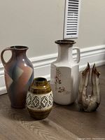 Four Mid-Century Modern West German fat lava vases in different shapes and glazes displayed on floor near wall vent