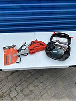 Black & Decker NaviGator electric saw, extra blades, and mouse sander on white table outside