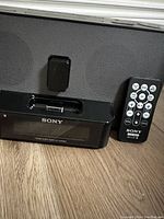 Front view of black Sony Dream Machine clock radio with digital display and remote control beside it
