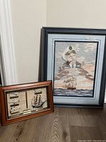 Two framed pieces: larger crewel needlepoint artwork of a sea captain with ship, smaller framed nautical knots and map display.