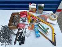 Photo of assorted garage tools and household repair items including saw, glue, caulk, screwdrivers, pest control traps, and paint stripper.