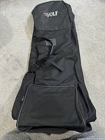 Black travel golf bag closed, showing front zippered pocket and carry handle.