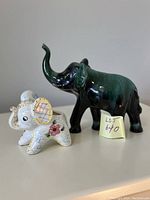 Photo showing two elephant figurines, one larger dark green Blue Mountain Pottery piece and one smaller colorful ceramic planter elephant
