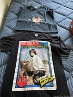 Top image showing two black graphic T-shirts laid flat on a mattress, one with David Bowie design, one with Star Wars Luke Skywalker design