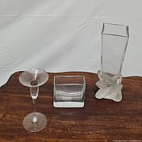 All three items displayed on wooden surface: tall square vase, small rectangular vase, and pedestal candlestick holder