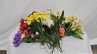 Wide shot showing assortment of stemmed artificial flowers in various colors and floral styles