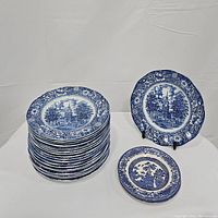 Stack of 20 Liberty Blue dinner plates with one plate displayed on a stand and 1 Blue Willow plate nearby