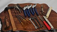 Top view showing all tools in the bundle arranged on wooden surface including pruning shears, wrenches, pliers, screwdrivers, hammer, scissors and putty knife.