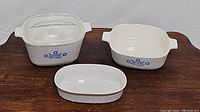 Photo showing all three casserole dishes including lidded square dish with blue cornflower pattern, 8x8 square dish with blue cornflower pattern, and oval white French-style dish.