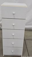 Photo showing full frontal view of the white chest with closed five drawers.