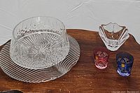 Photo of all crystal serving pieces including two colored shot glasses, a tulip-shaped dish, a round serving bowl, and a leaf pattern platter on a wooden surface.