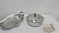 Three serving pieces shown: hammered aluminum tulip trays, casserole dish with tulip lid and handles, and leaf shaped brass footed dish.