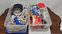 Two clear plastic tubs, one with black electrical tape and glue dispenser with cords, the other with various tubes of adhesive caulk, sealants and repair compounds.