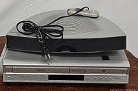 Front and top of Soundmatters MainStage single speaker sound system with power cord and wired remote, placed on top of Toshiba DVD/VCR recorder.