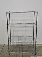 Front view of the 3 tier stainless steel metal rack showing the three wire grid shelves and vertical poles.