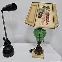 Photo showing both lamps side by side: green depression glass lamp with grape motif shade and black Ottlite desk lamp with adjustable arm