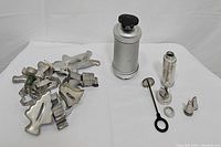 Cookie press, cake decorator spatula and attachments, and cookie cutters grouped and displayed on white background.