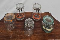 Overview of six vintage French glass canister jars on wooden surface, showing variety of sizes and lids with wire clamp closures.