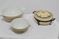 Two Pyrex mixing bowls and retro covered casserole dish with stand, side view