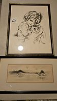 Overall view of both framed artworks showing child and dog sketch and Maine coastal landscape.