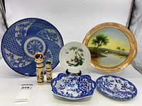 All items shown together including two wooden dolls and five pieces of chinaware, displayed on stands and flat surface.