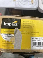 Photo of the box label showing Impact brand, model BGS-S12-V2, contents list including 2 stands, 4 crossbars, canvas bag, and manual