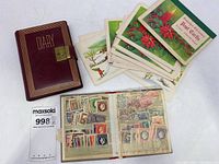Photo of the diary, stamp collection book open with visible stamps, and stack of postcards.
