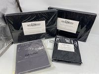 Photo showing multiple packaged sheet sets including black Royal Sateen sheets and a Calvin Klein set.