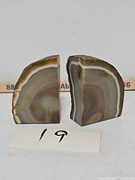 Pair of geode bookends shown from front with polished face displaying concentric bands and natural rough edges visible from side.