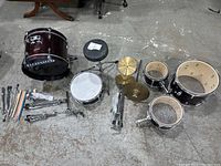 Top-down view of five drums, three cymbals, hardware and sticks laid out on floor