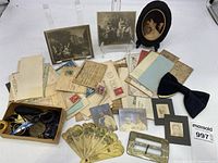 Wide view of the lot showing an array of old letters, photographs, decorative fans, buckles, a black bow tie, and a box with buttons and other small items.