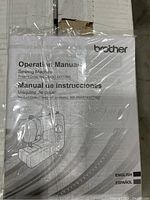 Operation manual in plastic wrapping with Brother logo and instructions in English and Spanish.