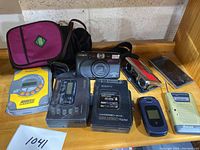 Lot overview showing all items including Walkmans, camera, phone, radio, binoculars, and carrying case